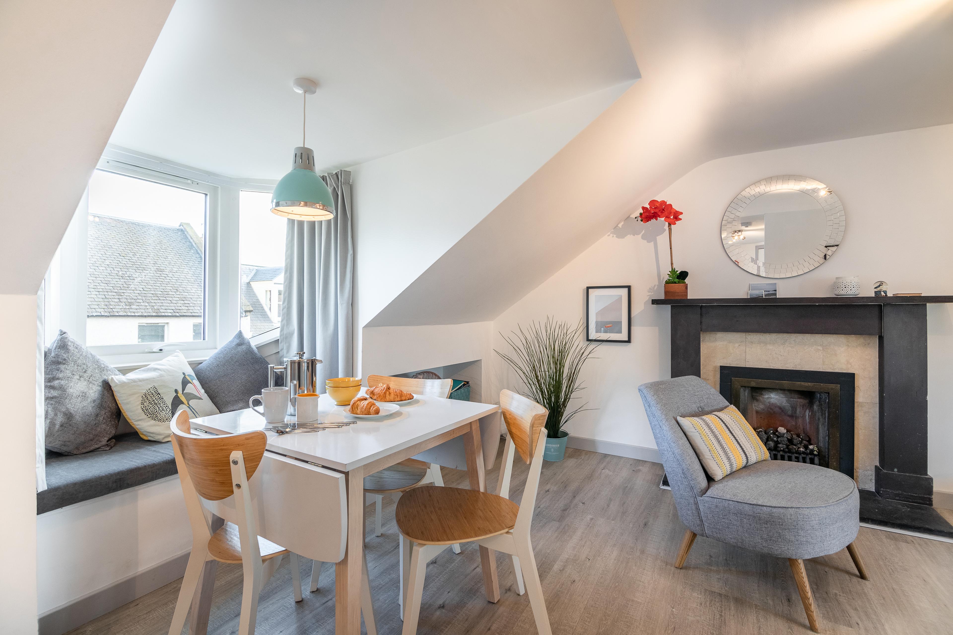 Bright attic-style lounge with fireplace, dining nook, and cozy window seat