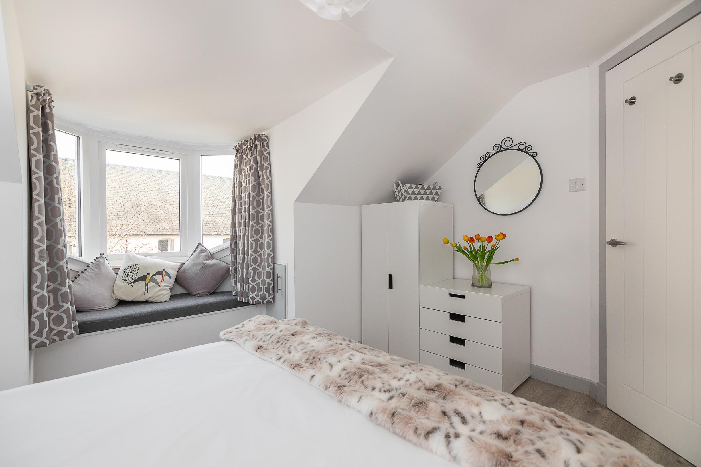 Bright bedroom with cozy window seat and elegant modern storage